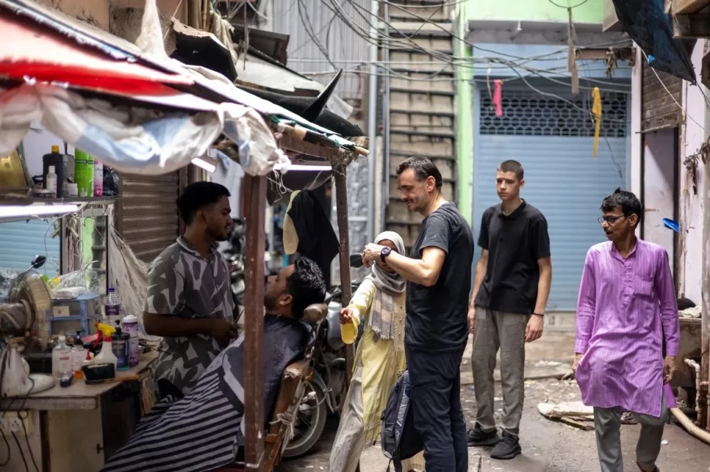 Tourists interacting with a local barber on a Dharavi local tour in Dharavi slum Mumbai by Cityscape Mumbai Tours