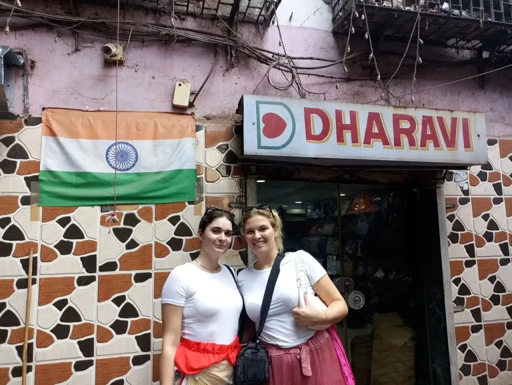 Two tourists posing in front of the Dharavi sign during a Dharavi local tour by Cityscape Mumbai Tours Mumbai