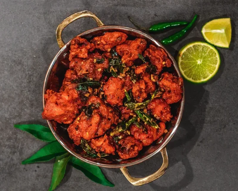 Spicy Chicken 65 garnished with curry leaves, served in a steel kadai with lime and green chillies - Cityscape Mumbai Tours food guide