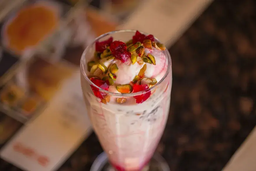 Rose Falooda topped with ice cream, pistachios and rose petals served in a tall glass - Cityscape Mumbai Tours food guide