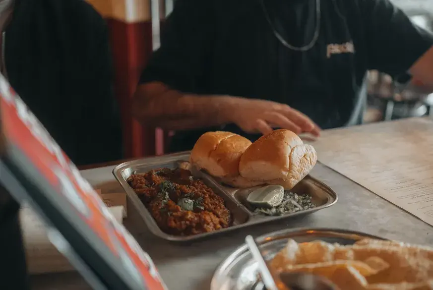 Spicy minced meat Kheema curry served with soft pav buns on a steel plate - Cityscape Mumbai Tours food guide