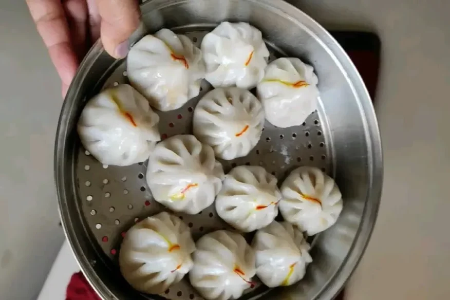 Steamed Ukadiche Modak with saffron strands, served on a steel steamer plate - Cityscape Mumbai Tours food guide