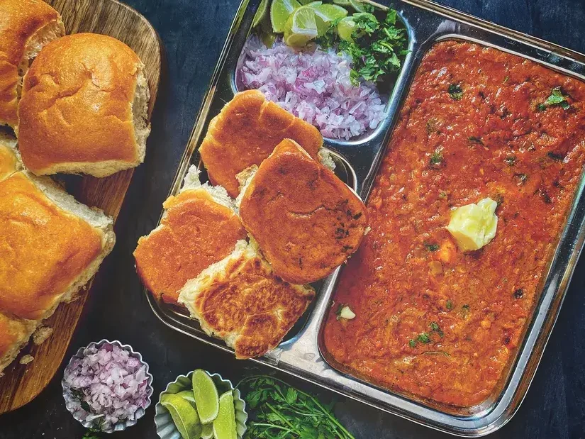 Buttery Pav Bhaji served with toasted pav, chopped onions, lime and coriander in a steel plate - Cityscape Mumbai Tours food guide