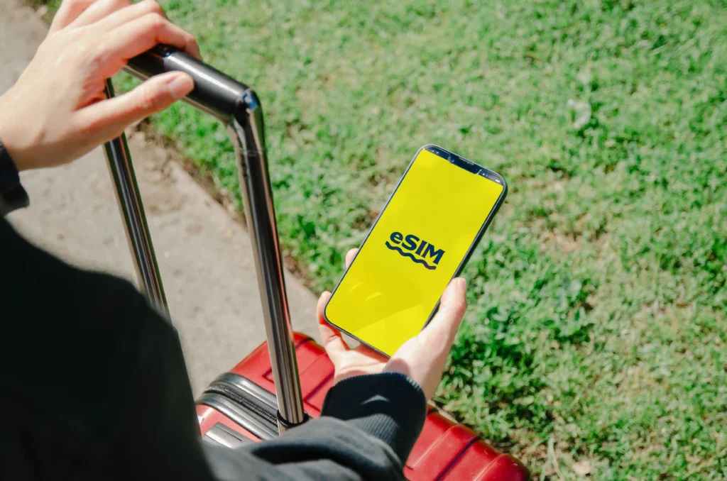 Traveller holding a red suitcase and activating an eSIM on a smartphone, showing an easy alternative to a physical Indian SIM card for foreigners in India.